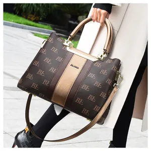 Detail of a brown tote bag with BL pattern and gold logo held by a model on the street