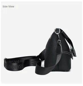 Side view of black lychee leather crossbody bag with wide nylon strap and silver hardware