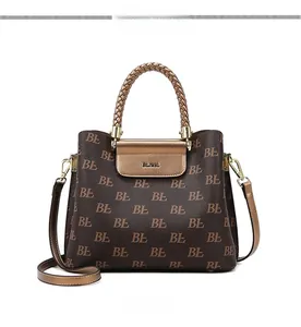 Close-up of monogram pattern tote with brown woven handles and gold metal buckle