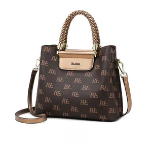 Side view of dark brown tote bag with logo print and woven handles on white background