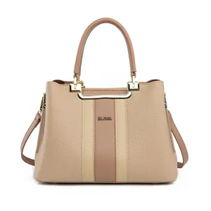 Detail of beige tote bag with brown stripe, gold hardware, and pebble leather texture