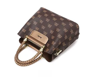 Close-up of printed monogram texture and brown braided handle on this tote bag