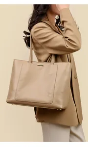 Detail of khaki leather tote bag with lychee texture and metallic gold trim accents