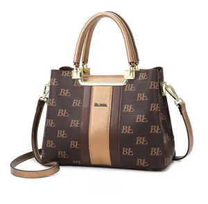 Detail view of large tote bag with brown monogram pattern and champagne gold stripe