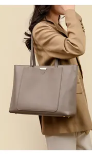 Detail of taupe pebbled leather tote bag with gold hardware and protective feet