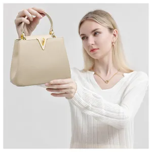 Detail view of cream-colored pebble leather bucket bag with gold V-shaped hardware
