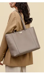 Detail of taupe pebbled leather tote bag featuring gold hardware and protective feet