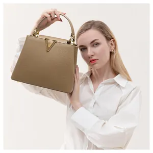 Detailed view of taupe lychee leather handbag with elegant gold V metal clasp detail