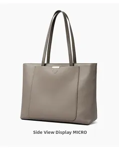 Side view of taupe leather tote bag with grainy texture and golden metal plate detail