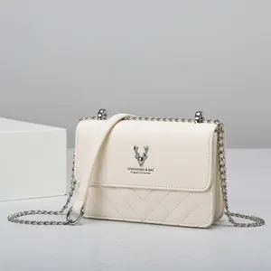 Detailaufnahme der beige Umhängetasche mit silbernem Hirsch-Logo und Steppmuster