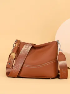 Caramel brown leather hobo shoulder bag with wide fashion strap on a minimalist background