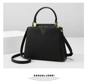 Detail of crocodile pattern texture and gold V-shaped clasp on black tote handbag