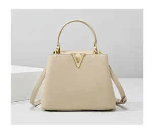Detail of beige lychee grain leather bucket bag with gold V-shaped metal hardware