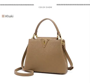 Detail of khaki bucket bag with lychee texture and gold V-shaped metal hardware