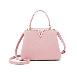 Close-up of pink lychee leather texture and golden V-shaped logo on the bucket bag
