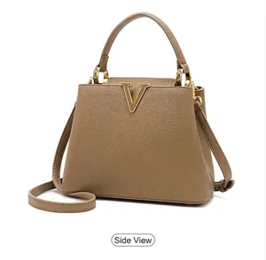 Detail view of khaki pebbled leather handbag with V-shaped golden metal hardware