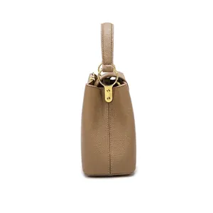 Side view of khaki lychee grain leather bucket bag with gold metal hardware details