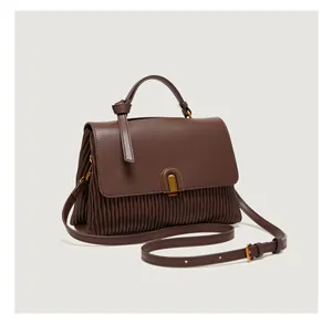 Detail view of the pleated leather texture and gold buckle on a brown tote bag