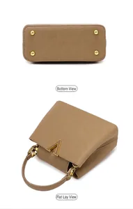 Detail view of brown pebbled leather handbag with gold metal V-clasp and bottom studs