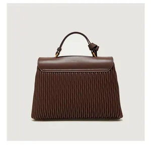 Detailed view of dark brown pleated faux leather handbag with golden hardware