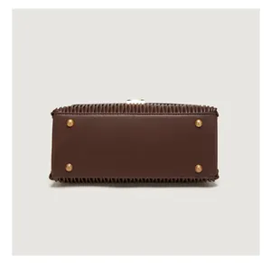 Detail view of dark brown leather handbag base with four protective gold metal rivets