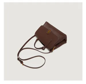 Detail of dark brown handbag with soft pleat texture and vintage gold metal buckle