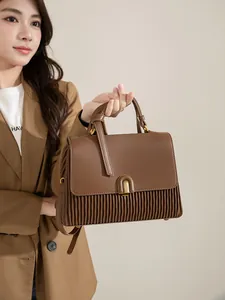 Detailed view of brown handbag with pleated texture and golden U-shaped buckle detail