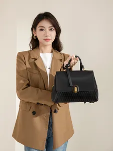 Detail of black pleated faux leather handbag with elegant gold arched metal buckle clasp