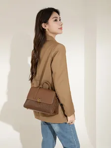 Detail of caramel brown leather handbag with elegant pleated design and gold buckle