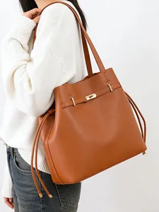 Minimalist brown faux leather bucket tote bag with gold twist lock and side drawstrings