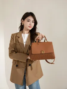 Detail of brown pleated leather handbag featuring a vintage gold clasp and textured flap