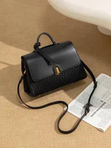 Elegant black leather handbag with pleated detail and golden horseshoe clasp on rug