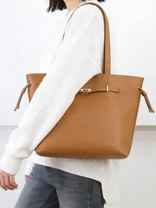 Detail of a brown leather tote bag with gold swivel lock and side drawstring accents