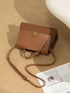 Macro detail of brown pleated leather handbag with golden U-shaped lock and shoulder strap