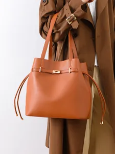 Close-up of tan leather bucket bag with golden twist-lock and drawstring detail