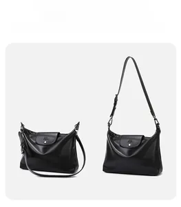 Detail of black leather tote bag showing adjustable shoulder strap and silver metal buckle