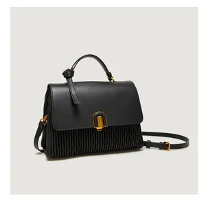 Detail of black leather handbag with accordion pleats and gold arched buckle
