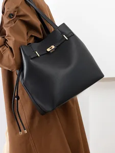 Detailed close-up of a black leather tote bag featuring a bright gold padlock and hardware
