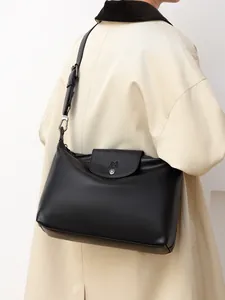 Detail of black faux leather tote bag showing a metal buckle, zipper and brand logo