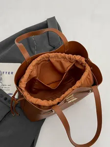 Brown leather bucket tote bag with drawstring inner pouch and gold clasp for women