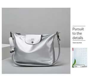 Detail view of silver metallic soft leather bag with M logo flap and wide shoulder strap