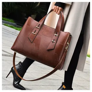 Detail of dark brown leather tote bag with geometric stitching and gold hardware