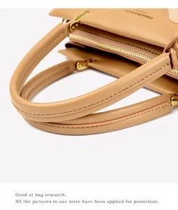 Detail of high-quality stitching and metal ring connectors on a caramel leather tote bag