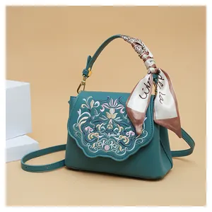 Detail of teal shoulder bag featuring elegant floral embroidery and a silk scarf handle wrap
