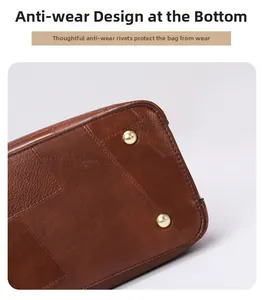 Detail view of the brown leather handbag base with protective gold metal studs