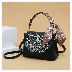 Detailed embroidery on vintage black leather crossbody bag with silk scarf handle