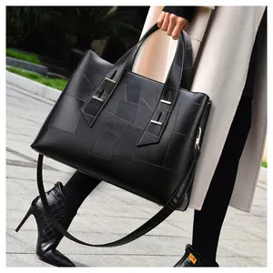 Detail shot of large black leather tote bag with geometric patchwork and metal hardware