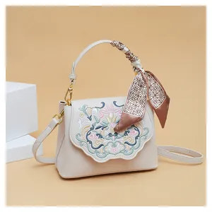 Detailed embroidery on a beige crossbody bag featuring elegant floral silk thread patterns