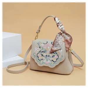 Detailed embroidery on vintage cross-body bag with silk scarf on handle and shoulder strap