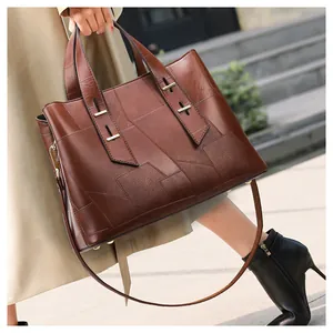 Detail of vintage brown tote bag with geometric leather patchwork and gold metal hardware